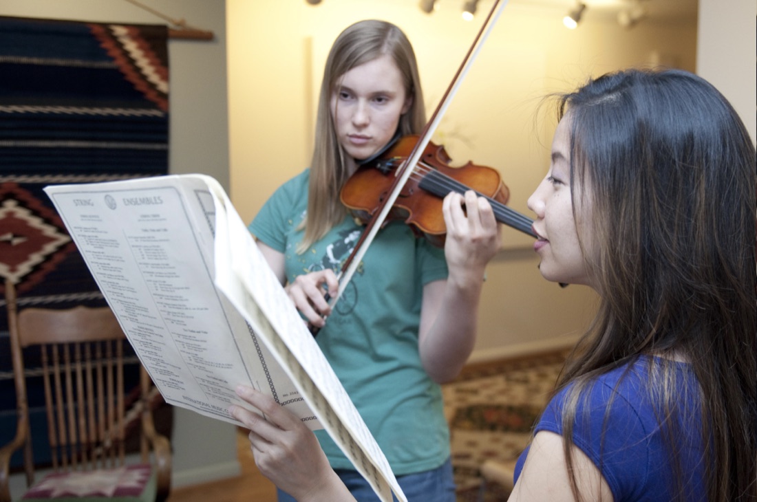 Two students reading sheet music together, one playing violin